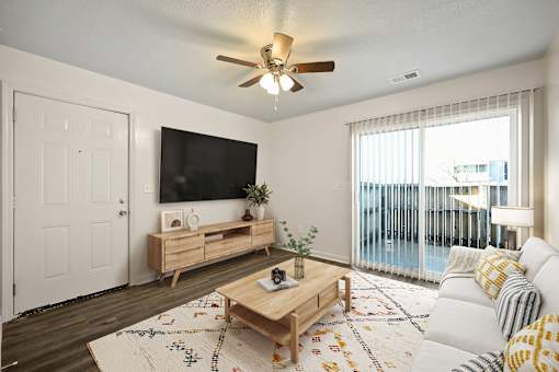 A living room with a flat screen TV, a white sofa, and a wooden coffee table.