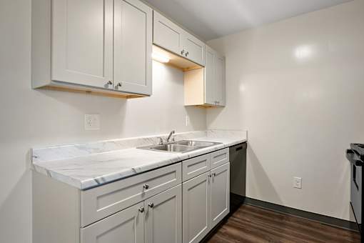 A kitchen with white cabinets and a marble countertop.