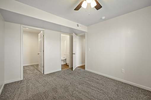 A room with a ceiling fan and carpeted floor.