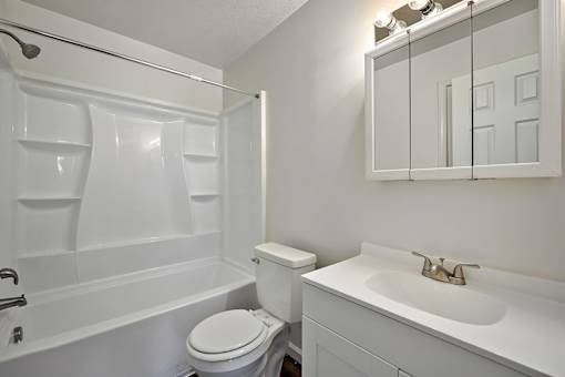 A white bathroom with a toilet, sink and bathtub.