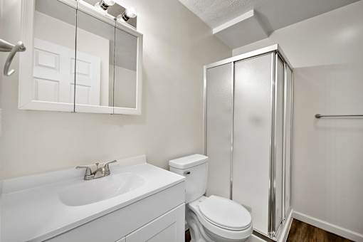 A white bathroom with a toilet, sink, and shower.