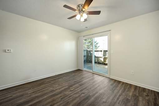 A room with a ceiling fan and wooden flooring.