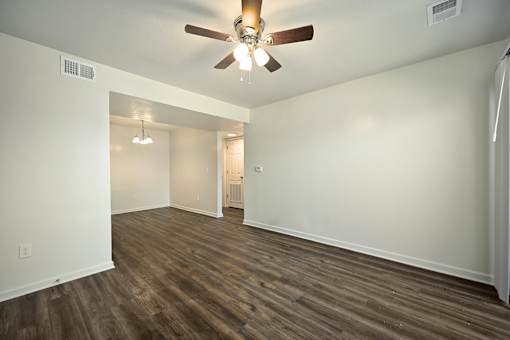 A room with a ceiling fan and wooden flooring.