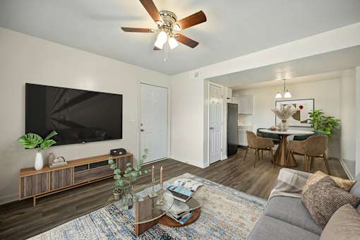 A living room with a grey couch, a wooden coffee table, a flat screen TV, and a ceiling fan.