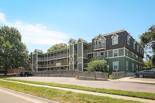 A green apartment building with a car parked in front.