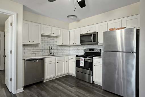 A kitchen with a refrigerator, oven, and microwave.