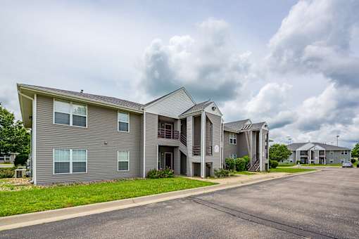 Apartment complex with multiple buildings and a parking lot in front.