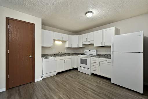 A kitchen with white appliances and wooden floors.