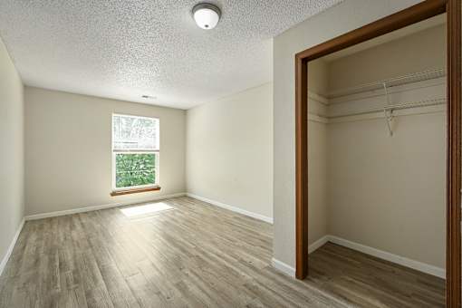 A room with a window and a wooden floor.