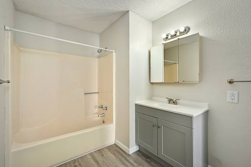 A bathroom with a white sink and a beige tub.