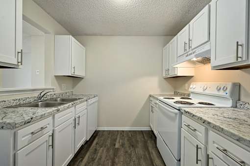 A kitchen with white cabinets and a granite countertop.