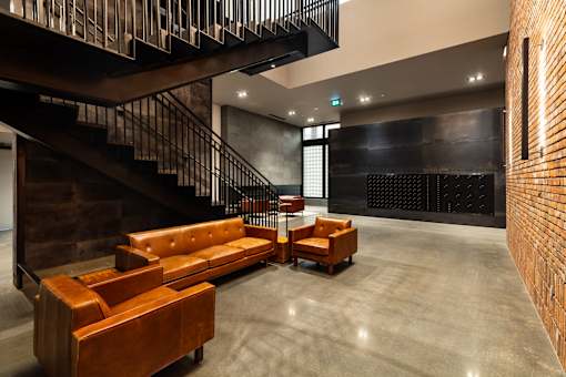 A brown leather couch sits in a room with a black staircase.at Raymond Block, Edmonton, AB T6E 3R7