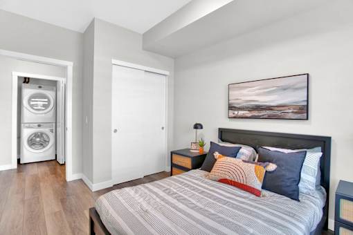A bedroom with a bed, nightstand, and a painting on the wall.