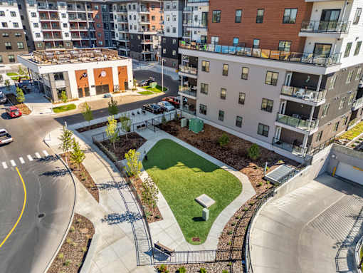 A view of a city street with apartment buildings and a small park.