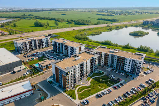 A bird's eye view of a residential area with apartment buildings and a parking lot.