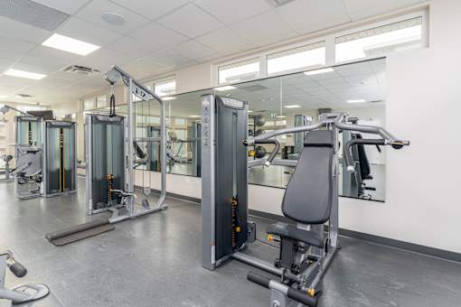 A gym with a variety of equipment including treadmills, stationary bikes, and weight machines. at G17 Apartments at Tamarack, Edmonton, Alberta