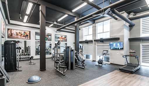A gym with a variety of equipment including treadmills, weights, and exercise machines.