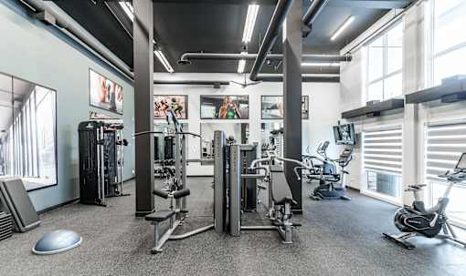 A gym with a variety of equipment including treadmills, weights, and exercise bikes.