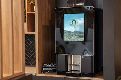 A coffee machine with a digital display showing a green landscape.