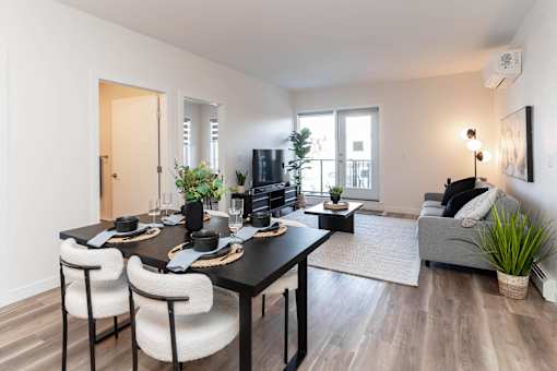A modern dining room with a black table and white chairs.at Vibe Apartments at Arbour Lake, Calgary  