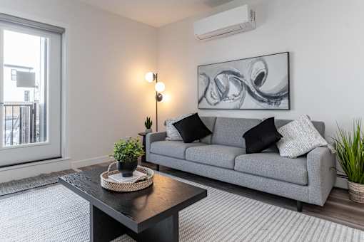 A living room with a grey couch, a black coffee table, and a large abstract painting on the wall.at Vibe Apartments at Arbour Lake, Calgary, AB T3G 4J2  