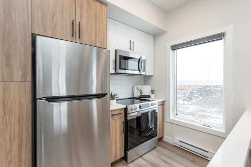 A modern kitchen with a stainless steel refrigerator and oven.at Latitude 49 Townhomes, Manitoba