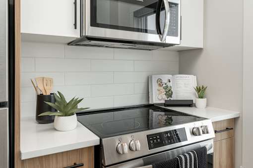 A modern kitchen with a black stove top and white countertops.at Latitude 49 Townhomes, Winnipeg