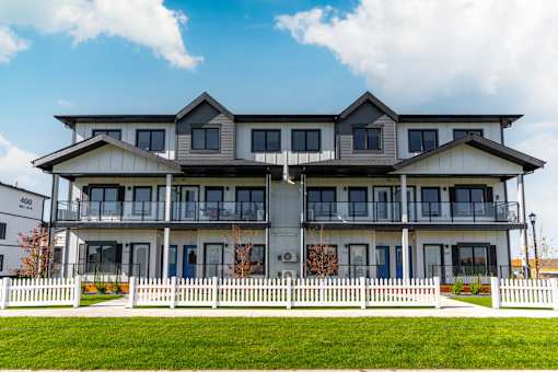 A large white building with a balcony on the second floor.at Latitude 49 Townhomes, Winnipeg, R3X 0M1