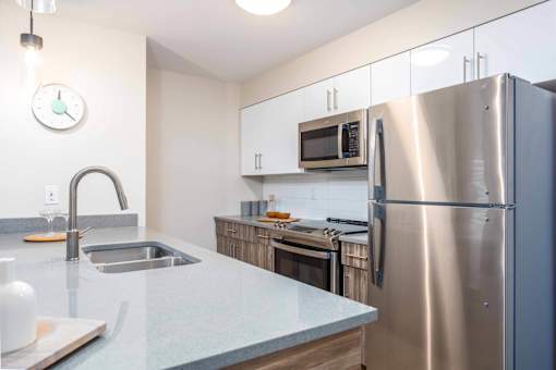 A kitchen with a stainless steel refrigerator, microwave, and sink. at G17 Apartments at Tamarack, Edmonton, Alberta
