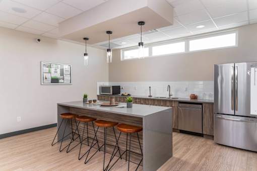 A modern kitchen with a bar area and stools. at G17 Apartments at Tamarack, Edmonton, AB