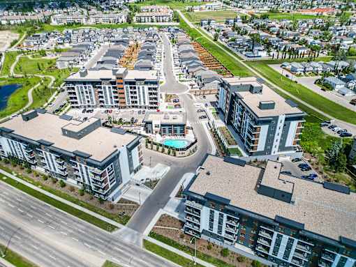 A bird's eye view of a residential area with apartment buildings and a pool.