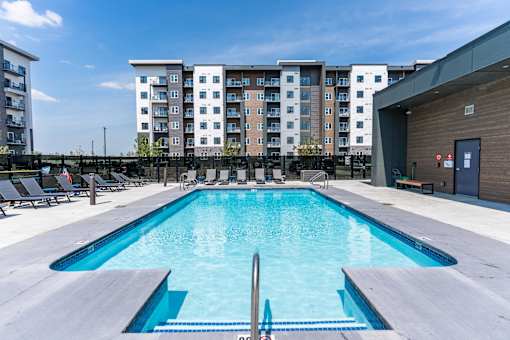 A large swimming pool in front of apartment buildings.