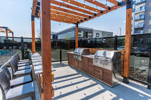 A wooden pergola with a grill underneath it.
