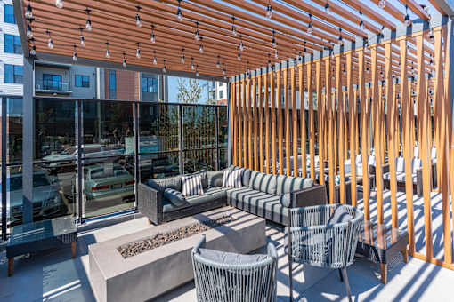 A wooden patio with a couch, chairs, and a fire pit.