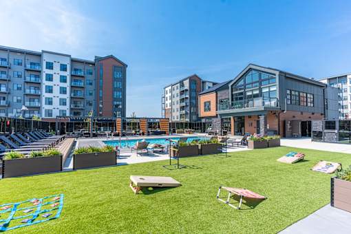 A large grassy area with a pool and sun loungers in front of apartment buildings.