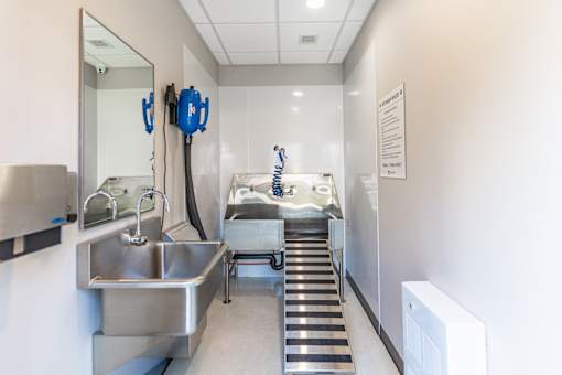 A clean, well-lit hospital room with a sink, mirror, and medical equipment.