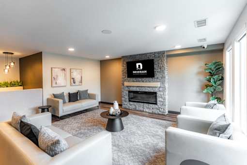 A living room with a grey sofa, a grey rug, a black coffee table, a fireplace, and a TV mounted on the wall.