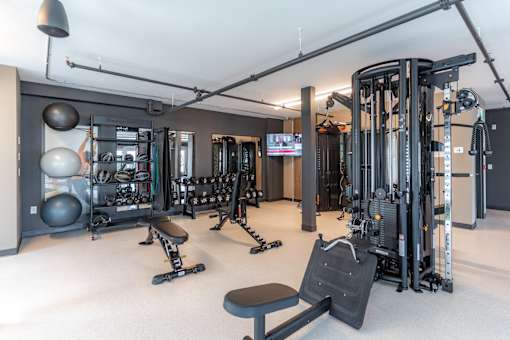 A gym with a variety of equipment including weights, a bench, and a television.