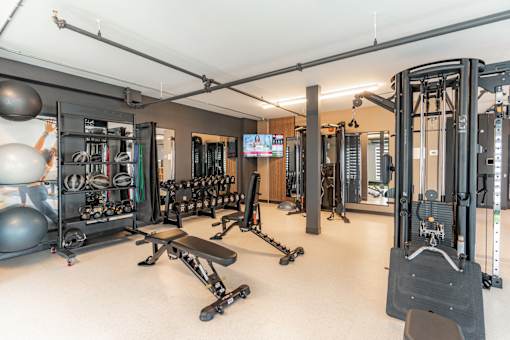 A gym with a variety of equipment including weights and a bench.