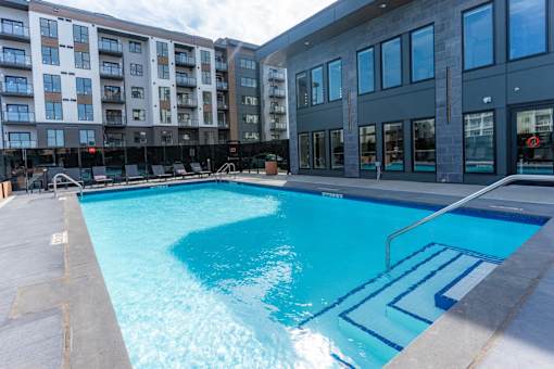 A swimming pool in front of a building with a glass facade.