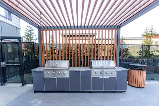 A large outdoor grill is in front of a wooden fence.