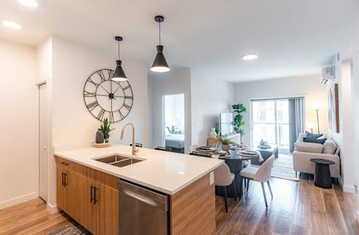 A kitchen with a large island and a dining area with chairs.