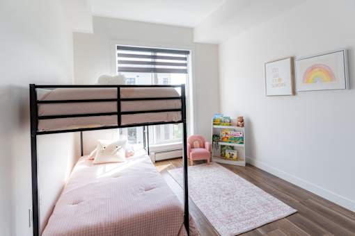 A child's bedroom with a bunk bed and a pink chair.