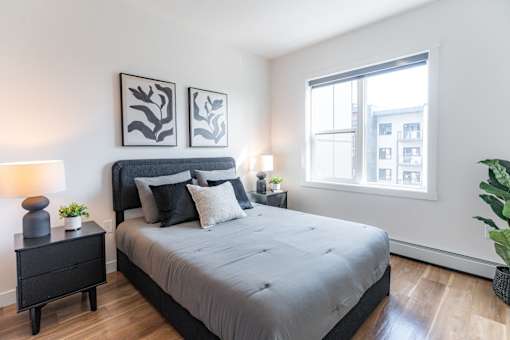 A bedroom with a large bed and a window overlooking a city.