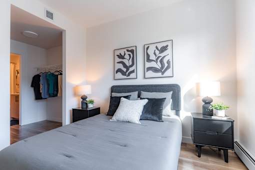 A bedroom with a large bed and two side tables with lamps.