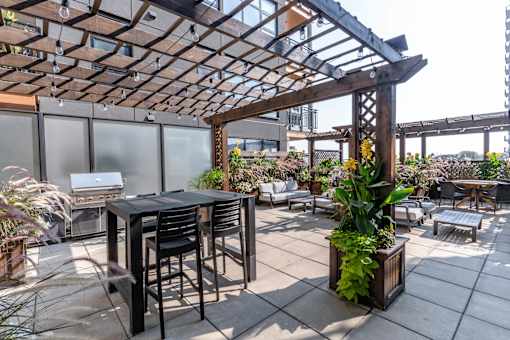 A patio with a table and chairs under a wooden pergola. at Raymond Block, Edmonton, AB
