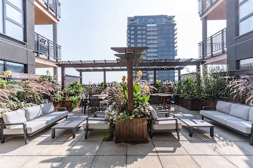 A patio with white couches and a wooden table. at Raymond Block, Edmonton, AB