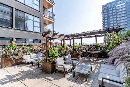 A patio with white furniture and a wooden pergola. at Raymond Block, Edmonton, AB