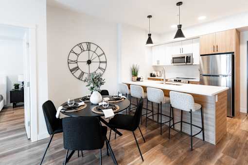 A modern kitchen with a dining table set for four.at Podium Apartments, Calgary, AB