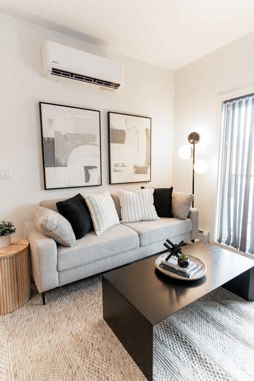 A modern living room with a grey sofa, a coffee table, and two framed pictures on the wall.at Podium Apartments, Calgary, AB